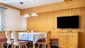 A dining area with wooden walls, a white table, and red chairs.