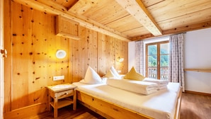A wooden cabin-style room with a bed, a desk, and a window with curtains.