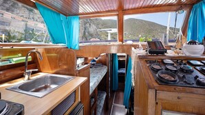 A compact kitchen with a sink, stove, and window overlooking a mountainous landscape. - Aloha Jak's Boat with Sea View, Wi-Fi, and Air Conditioning (Alassio)