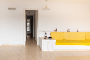 A room with a white sofa, a small white cabinet, and a doorway leading to another room.