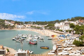 A coastal town with a marina, beach, and buildings along the shore.