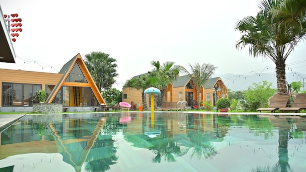 Un hôtel moderne doté d’une piscine, d’un espace extérieur aménagé et d’un jardin aux allures tropicales.