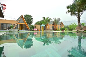 Ein modernes Hotel mit Schwimmbad, Außenbereich und tropischer Bepflanzung.