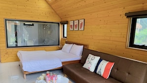 Une pièce confortable avec un lit, un canapé, une petite table avec des boissons et une fenêtre.