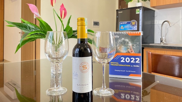 A table with a bottle of Saigon Premium Red Wine, two empty wine glasses, and a 2022 Digital Transformation for SMBs poster. - Quan Nhan Apartment (Hanoi)