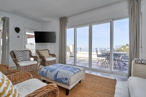 A spacious room with a large bed, two wicker chairs, a sofa, and a balcony with a table and chairs. - Holiday home 'Casa Mariposa' with sea views, large terrace and air conditioning (Almuñécar)