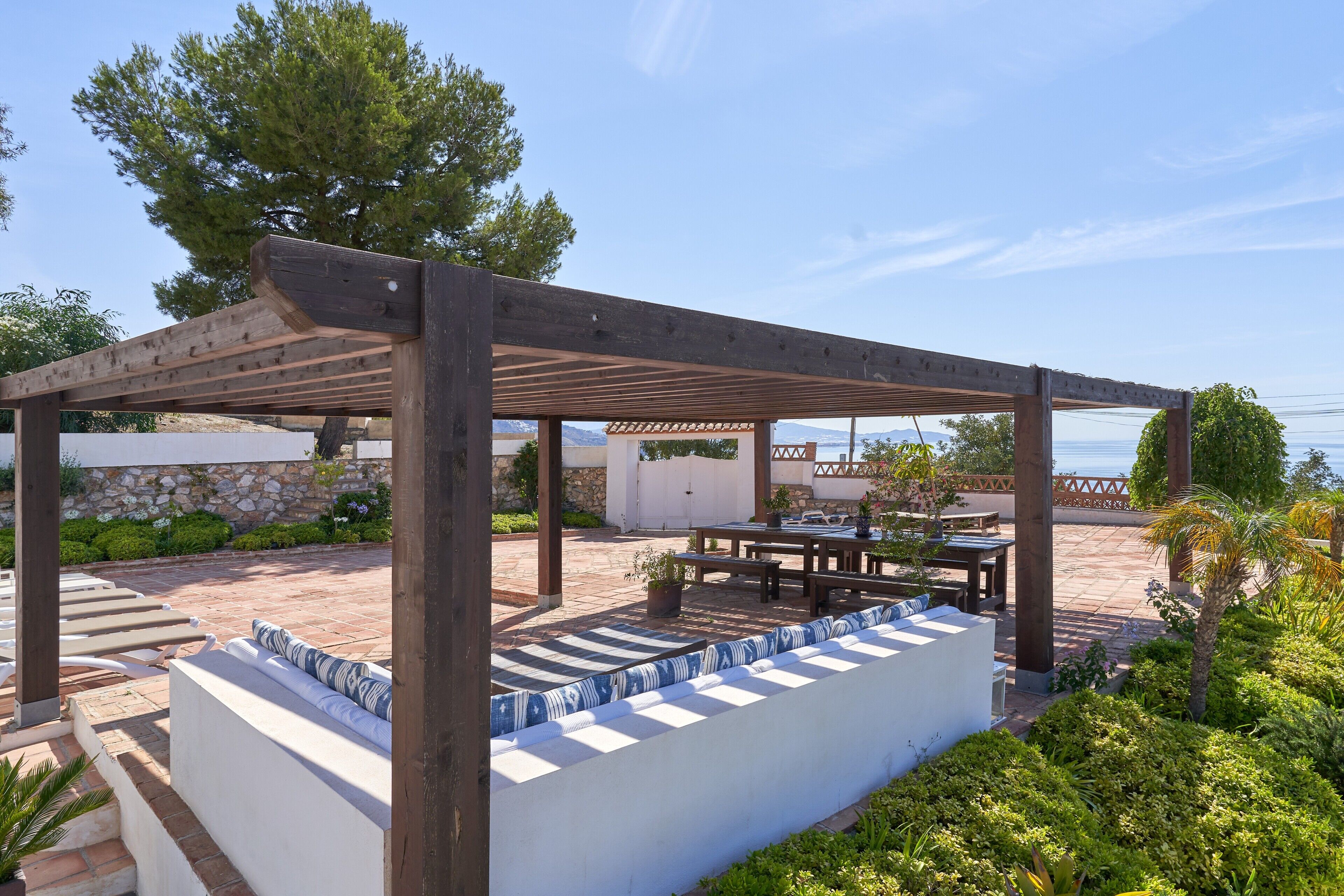 Een overdekt terras met een pergola, een zwembad en uitzicht op zee.