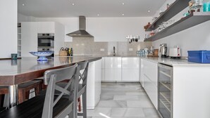 Een moderne keuken met witte kasten, een centraal eiland en een roestvrijstalen afzuigkap.