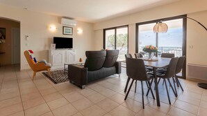 Un salon moderne avec un canapé, une table à manger, des chaises, un téléviseur et une vue sur le balcon.