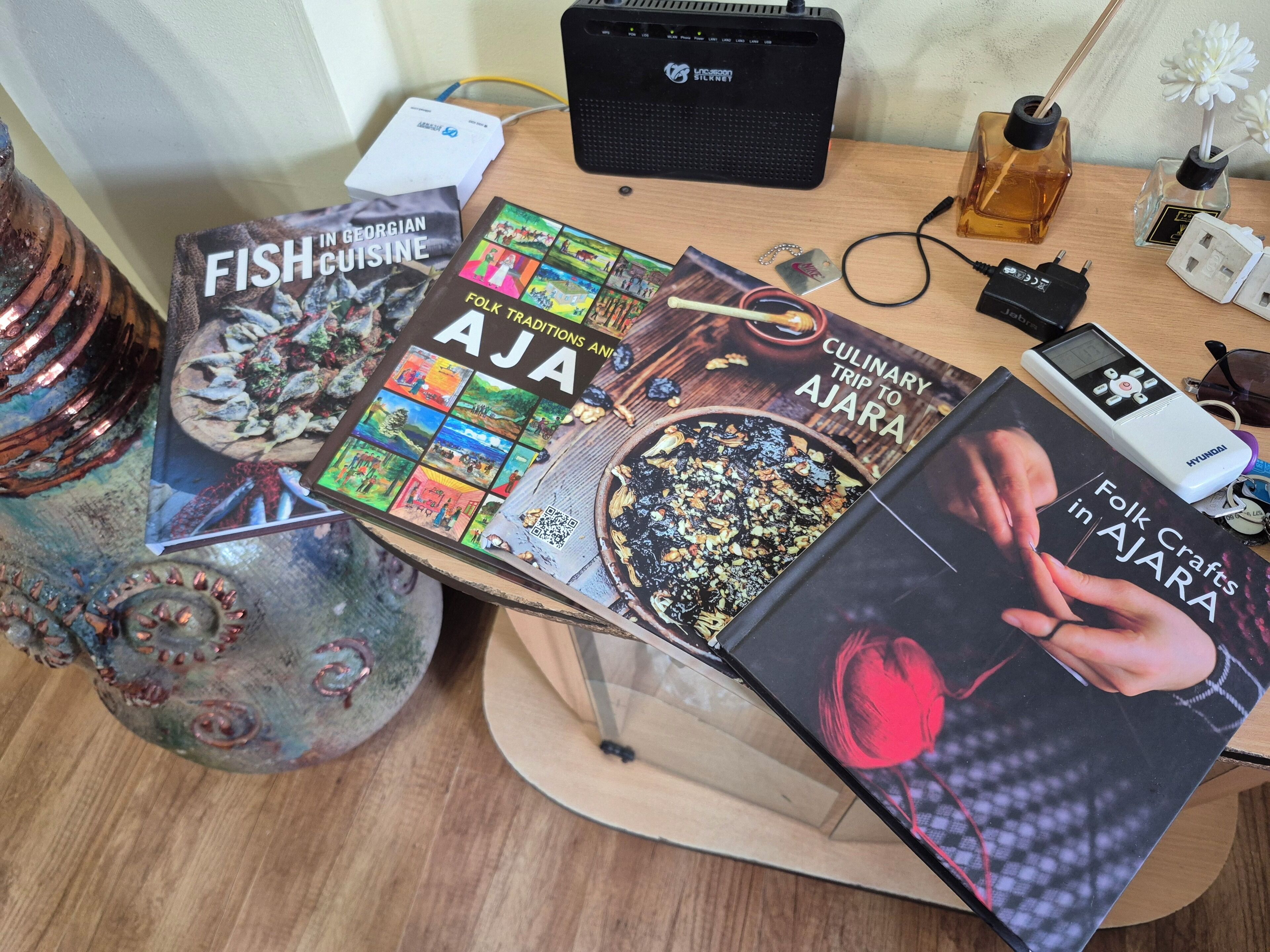 Un escritorio con libros, un altavoz, una regleta y objetos decorativos.