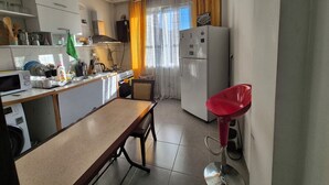 Une cuisine compacte comprenant une table à manger, un tabouret de bar rouge, un lave-linge et un réfrigérateur.