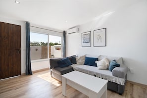 Un salon moderne avec un canapé, une table basse blanche et une grande fenêtre.
