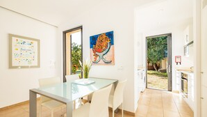 A modern kitchen with white cabinets, a glass table, and a dining area with chairs. - Villa 'Alfonsa' with Mountain View, Wi-Fi and Air Conditioning (pollensa)