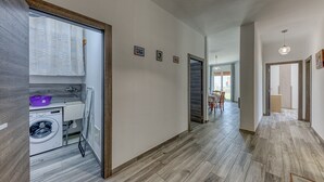 Un corridoio con lavatrice, zona pranzo e cucina sullo sfondo.