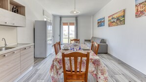 Una cucina moderna con zona pranzo, mobili in legno, frigorifero grigio e tavolo imbandito per quattro persone.
