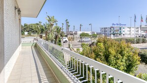 Un balcone con ringhiera bianca che si affaccia su un'area parcheggio e un edificio con la scritta 'Lido San Giovanni'.