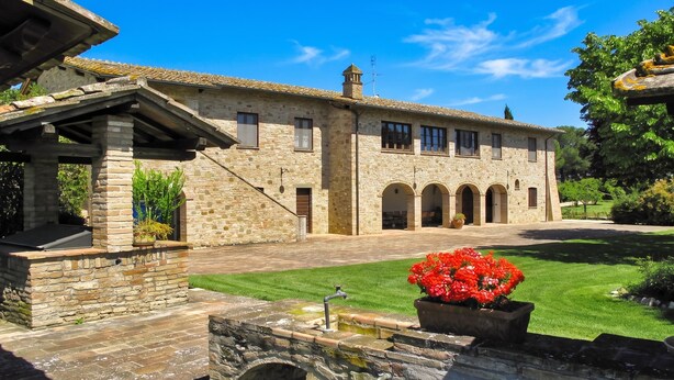 A stone building with a tiled roof, a stone archway, and a well-maintained lawn. - Villa del Colle (Torgiano)