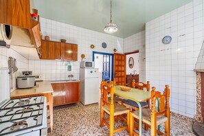 Una cucina con piano cottura a gas, mobili in legno, forno a microonde e tavolo da pranzo con sedie.