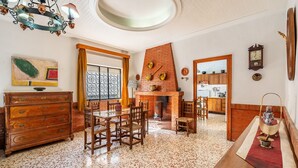 A dining area with a brick fireplace, wooden furniture, and a view into the kitchen. - Country House 'Casa Solariega Con Encanto' with Mountain View, Private Terrace and Wi-Fi (Padul)
