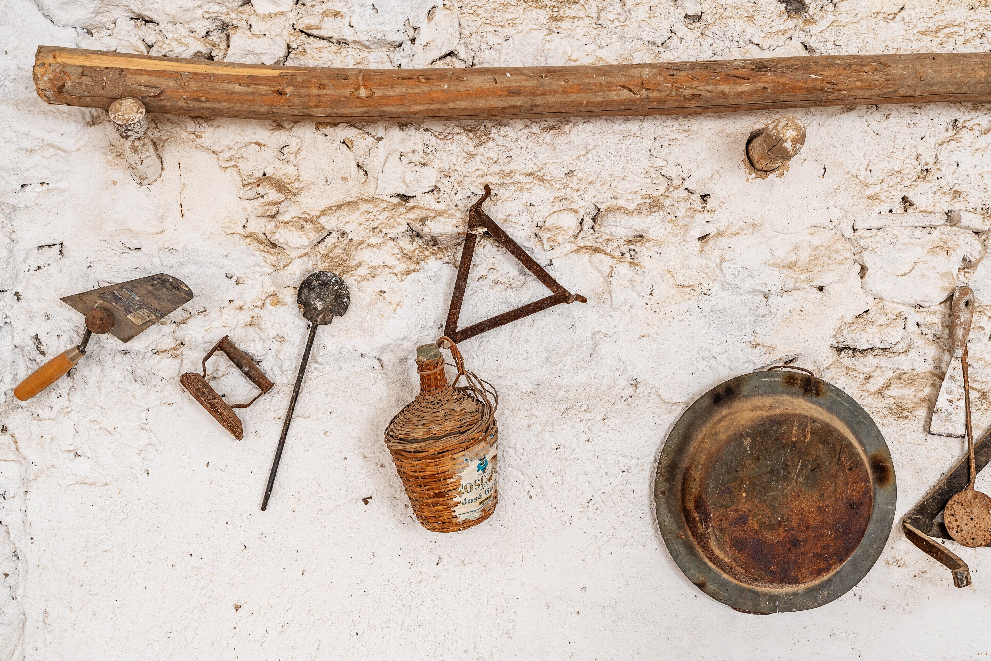 A rustic wall with various tools and a wooden beam.