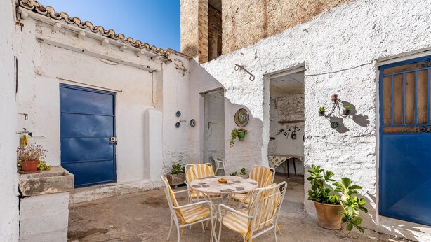 A courtyard with a round table and four chairs, a blue door, and potted plants. - Country House 'Casa Solariega Con Encanto' with Mountain View, Private Terrace and Wi-Fi (Padul)