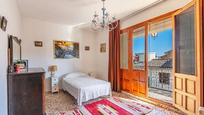A bedroom with a bed, a dresser, a chandelier, a painting, and a view through a sliding door. - Country House 'Casa Solariega Con Encanto' with Mountain View, Private Terrace and Wi-Fi (Padul)