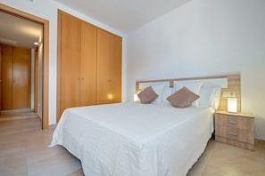A bedroom with a large bed, wooden wardrobe, bedside table, and a nightstand. - Apartment 'Sara' with Private Terrace, Wi-Fi and Air Conditioning (L'Aldea)