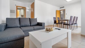 Un soggiorno moderno con un divano grigio, un tavolino da caffè bianco e un'area pranzo con sedie e tavolo.