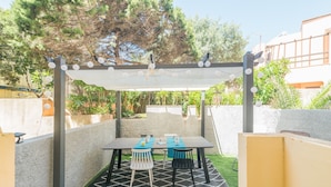 Eine Terrasse im Freien mit Tisch und Stühlen, umgeben von Mauern und Bäumen.