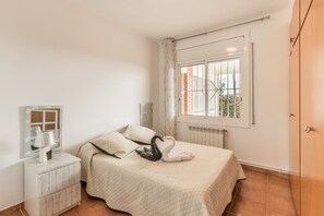 A bedroom with a bed, a nightstand, a mirror, a window with curtains, and a radiator. - Holiday Home 'Can Fogars' with Sea View, Private Pool and Wi-Fi (fogars de la selva)