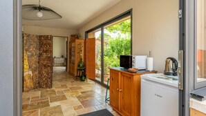 La cuisine est équipée d’un réfrigérateur Bosch, d’un four à micro-ondes et d’une bouilloire. On y trouve également un meuble en bois et une porte en verre donnant sur un balcon.