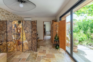 A hallway with a mosaic wall, a ceiling fan, a glass door leading to a garden, and a wooden cabinet. - Holiday Home 'Villa La Mireio' with Private Terrace, Wi-Fi and Air Conditioning (Malaucène)