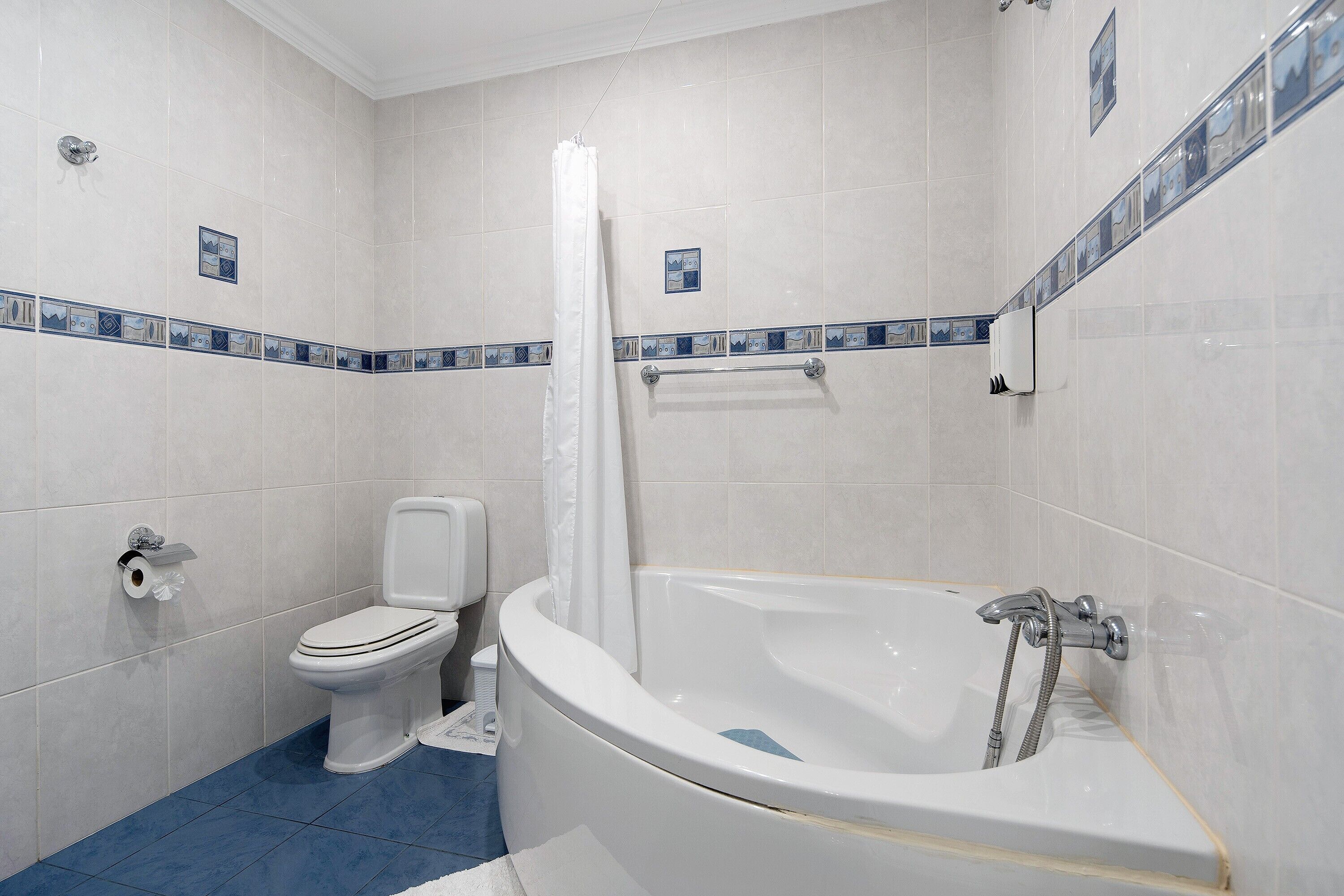 Une salle de bain équipée de toilettes, d’une baignoire et d’un rideau de douche.