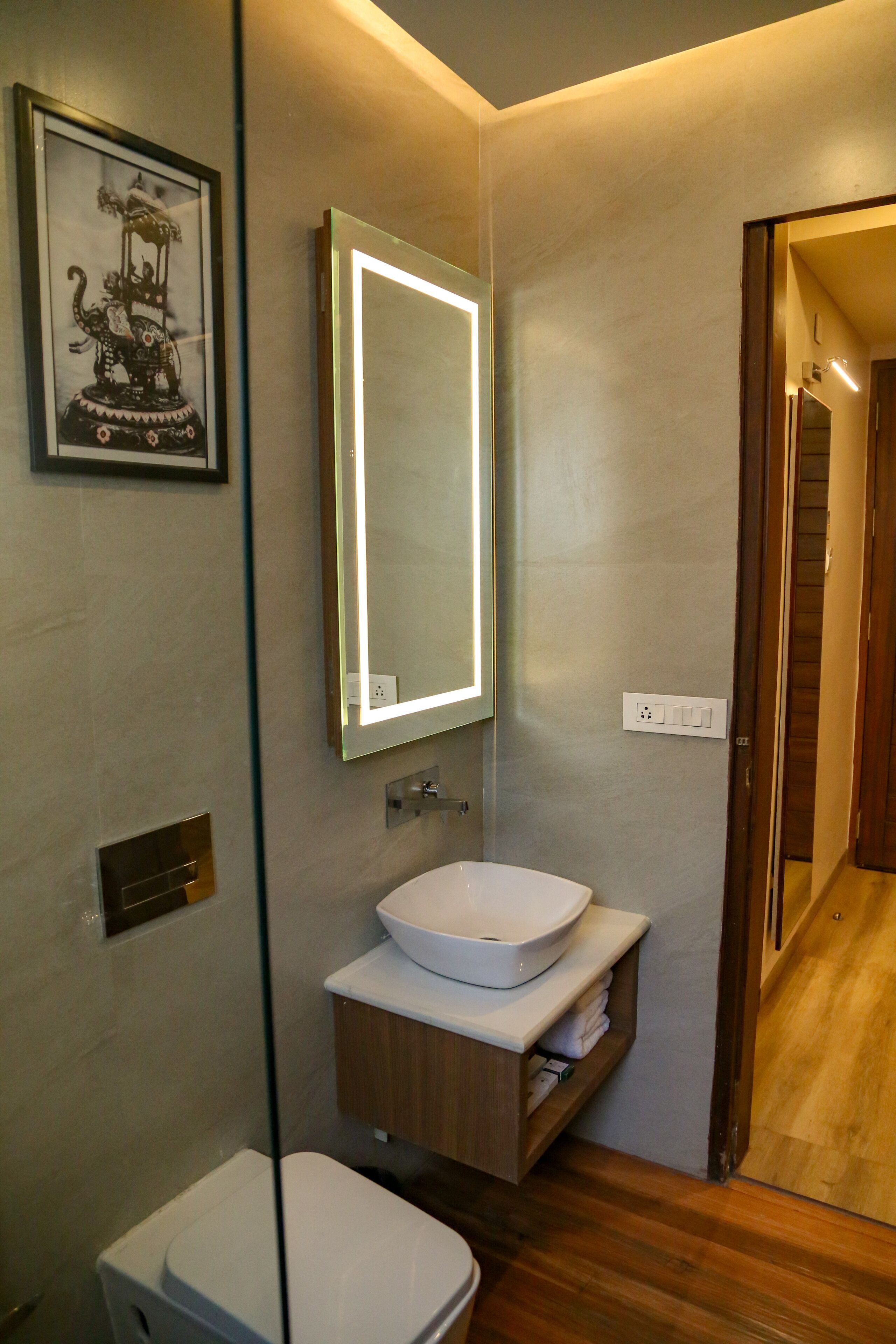 A modern bathroom with a white sink, a mirror, and a framed picture on the wall.