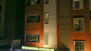Hotel de vários andares com fachada moderna, apresentando uma entrada destacada com porta de vidro e escadaria que leva à entrada.