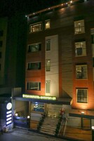 A multi-story hotel with a modern facade, featuring a prominent entrance with a glass door and a staircase leading to the entrance.