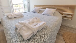 Un letto rifatto con cura, con una coperta a motivi, due cuscini e asciugamani piegati sul comodino.