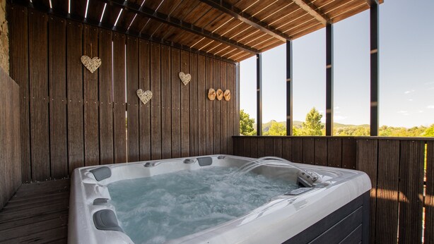 Una vasca idromassaggio con un pontile in legno e vista sul paesaggio.