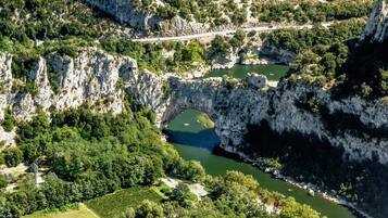 A mountainous landscape with a river, a bridge, and a vineyard.