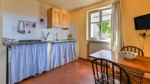 Una cocina con salpicadero de azulejos, estufa, lavamanos y una ventana con cortinas.