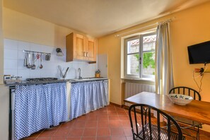 A kitchen with a tiled backsplash, a stove, a sink, and a window with curtains.