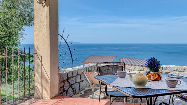 Una terraza con una mesa dispuesta para dos personas, con vista al mar.