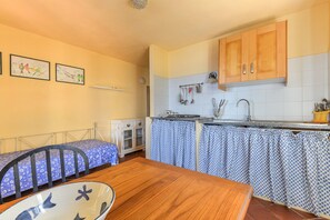 A compact kitchen with a dining area, a bed, and a small cabinet.