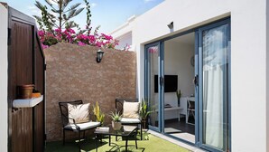 A patio with a stone wall, a wooden door, and a glass sliding door leading to an interior space.