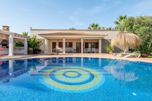 A swimming pool with a circular pattern, a covered patio with seating, and a building with a tiled roof. - Villa "Finca Son Manyo 225" with Mountain View, Private Pool & Wi-Fi (sa pobla)
