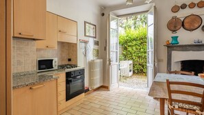 A kitchen with wooden cabinets, a microwave, an oven, and a dining area with a table and chairs.