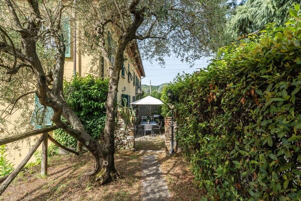A narrow pathway leading to a building with a covered outdoor seating area.