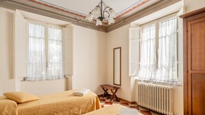 A room with two beds, a radiator, a wooden cabinet, and a mirror.