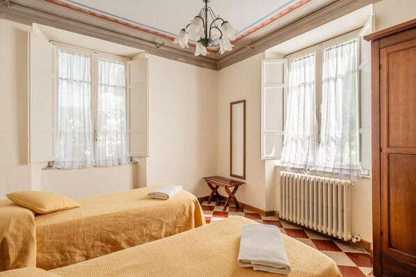 A room with two beds, a radiator, a wooden cabinet, and a mirror.
