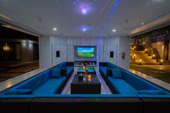 A modern living room with a large flat-screen TV, blue sofas, and a coffee table. - Bluemango Pool Villa & Resort Koh Samui (Koh Samui)